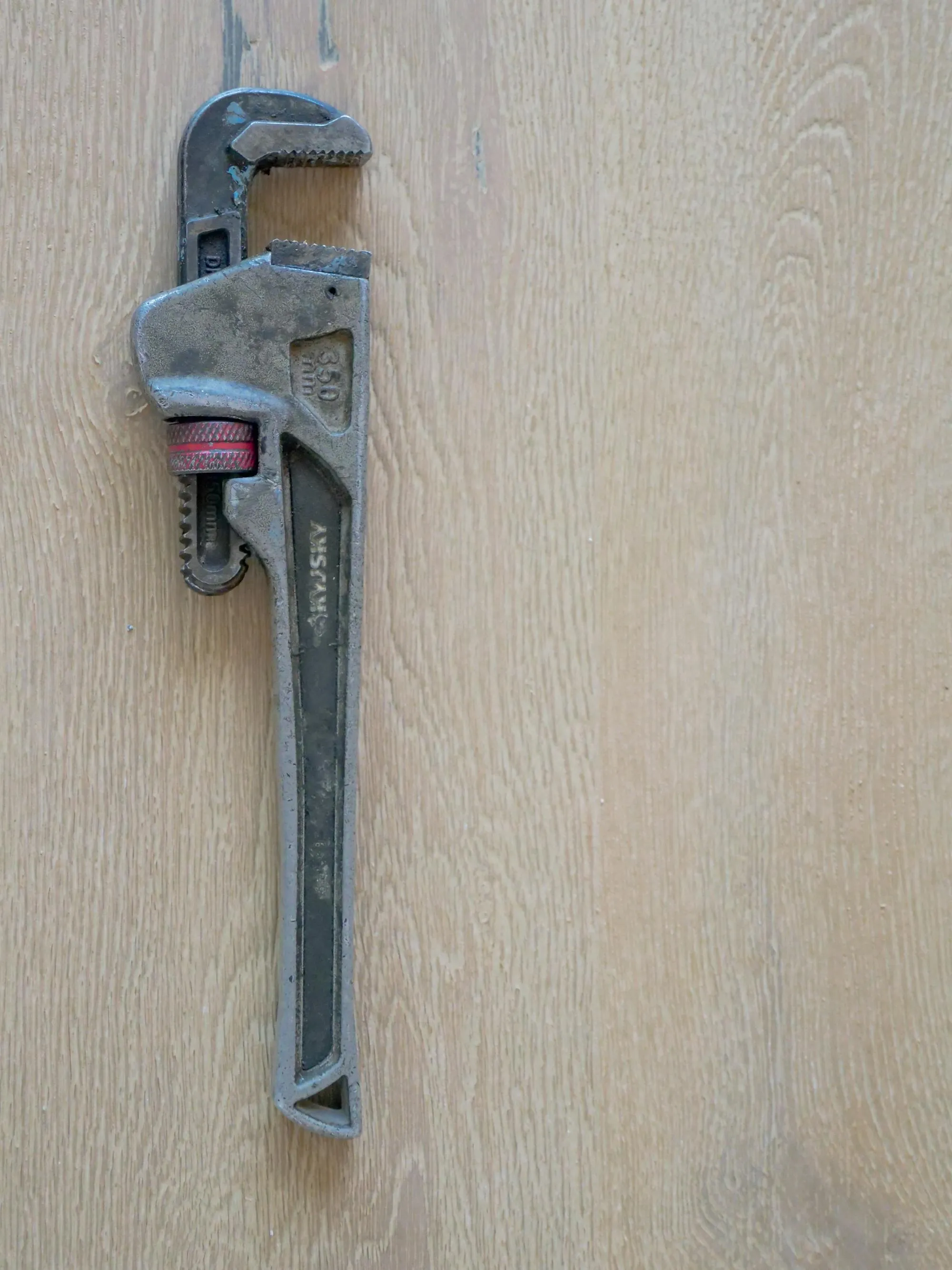 A pipe wrench on a clean workshop floor.