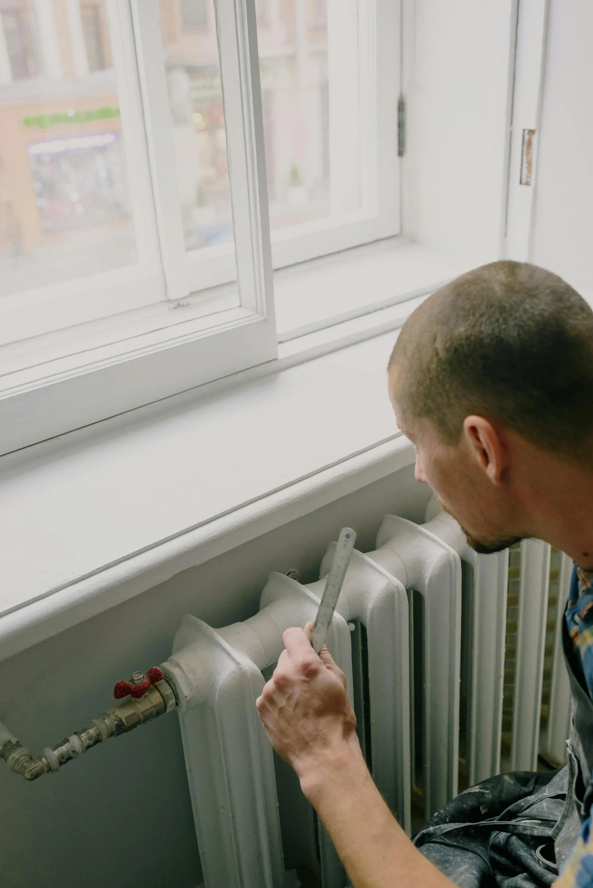 Heating engineer measuring a radiator in a Coventry property.